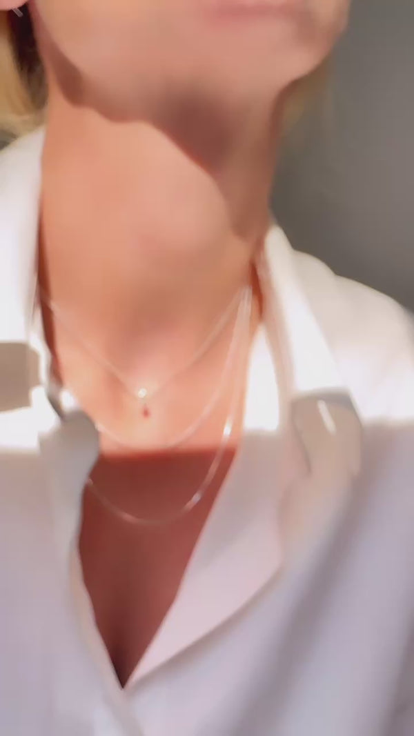 Tjej som bär ett kort diamanthalsband kombinerat med tunna kedjor - layering.