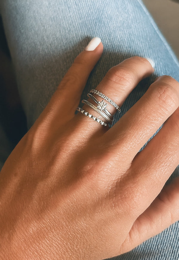 Tjej som bär silverringar och diamantringar i kombination
