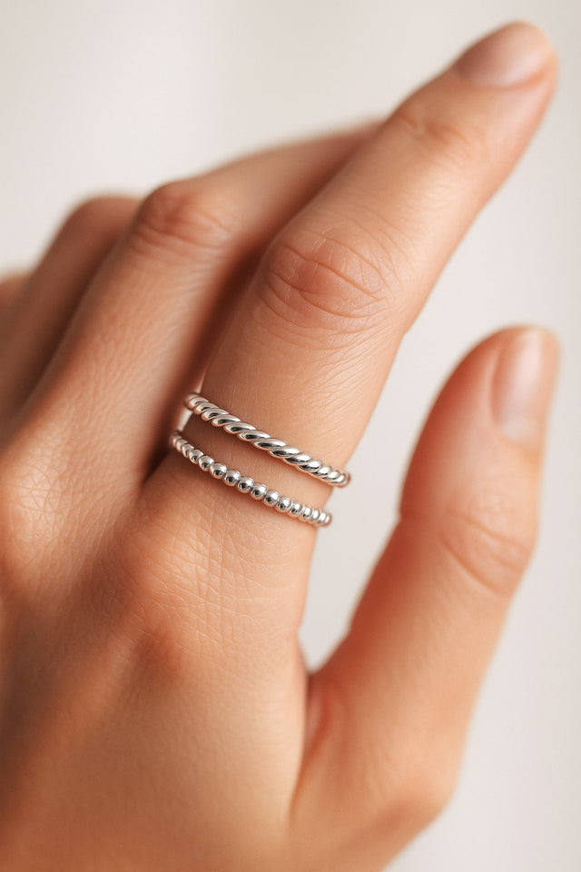 två silverringar i kombination. en ring med små silverkulor och en vriden silverring. bär på ett pekfinger.