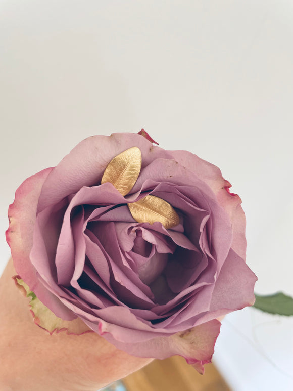 En ros med ett par guldörhängen i rosen.