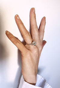 Hand med en silverring med knut som poppar på handen. 