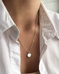 Kvinna som bär ett silverhalsband med berlock med diamantbokstav.  
