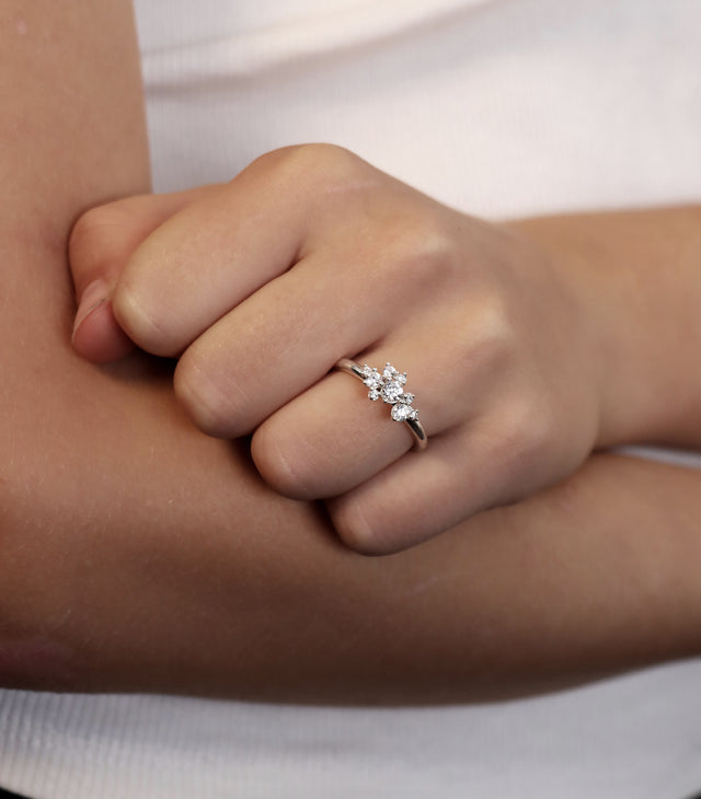 En tjej som bär en diamantring med flera diamanter i olika storlekar sammansatta som ett kluster. 