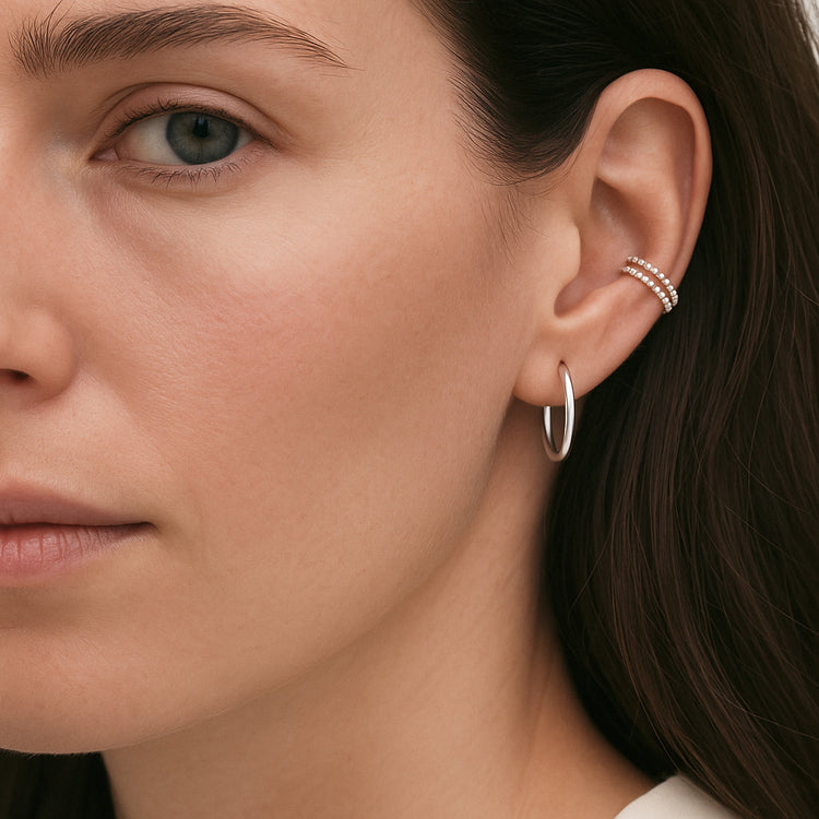Tjej som bär en ear cuff och en hoop ring i silver i samma öra. 