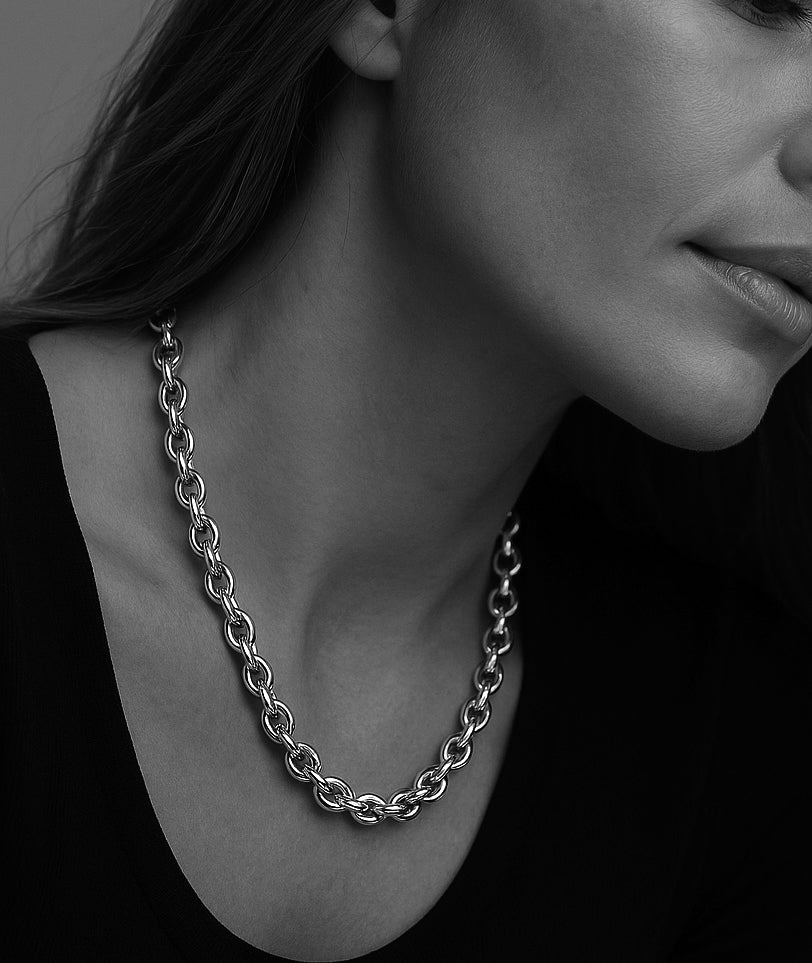 Kvinna som bär ett chunky kedjehalsband i silver. 