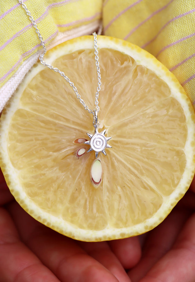 Silverhalsband med en liten sol placerad på en citron. 