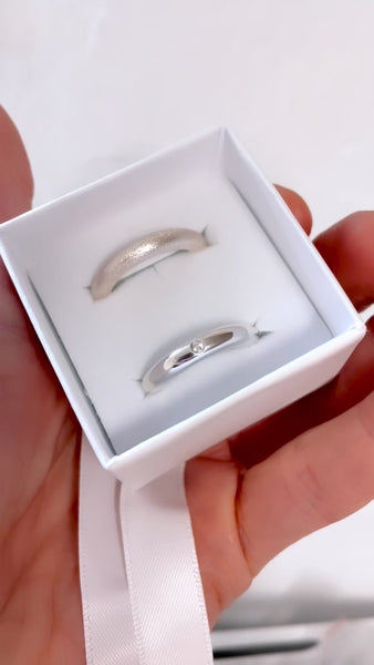 Två silverringar, en matt ring och en ring med diamant. 