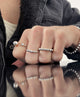 Tjej som bär flera silverringar på olika fingrar med silverkulor. 