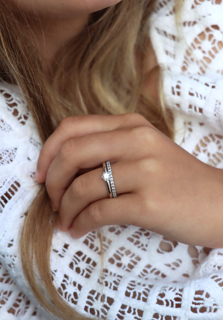 Tjej som bär två diamantringar som vigsel- och förlovningsring. Silverringar med diamanter. En alliansring med flera små diamanter och en ring med en diamant 0,25 ct. 