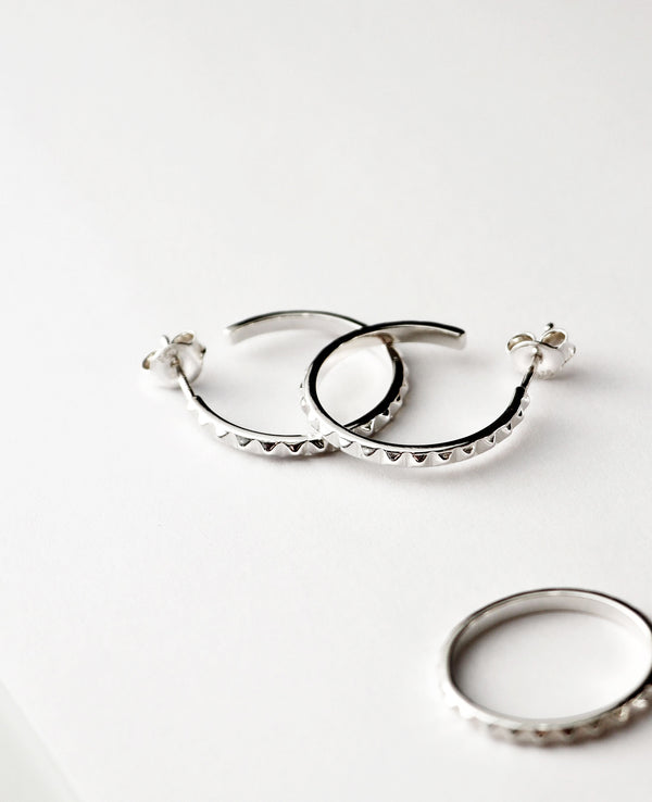 Silverörhängen med ringar som har små nitar längs med ringarna. 