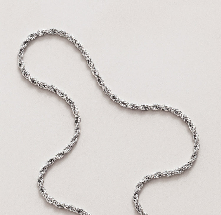 Silverkedja med vridna trådar som ett rep, ligger på ett bord. Modell Rope chain. 