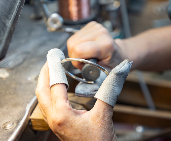 Ett silverarmband tillverkas och slipas med maskin i en verkstad.