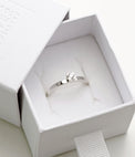 Silverring med 0,10 ct diamant placerad i en vit ringask. 