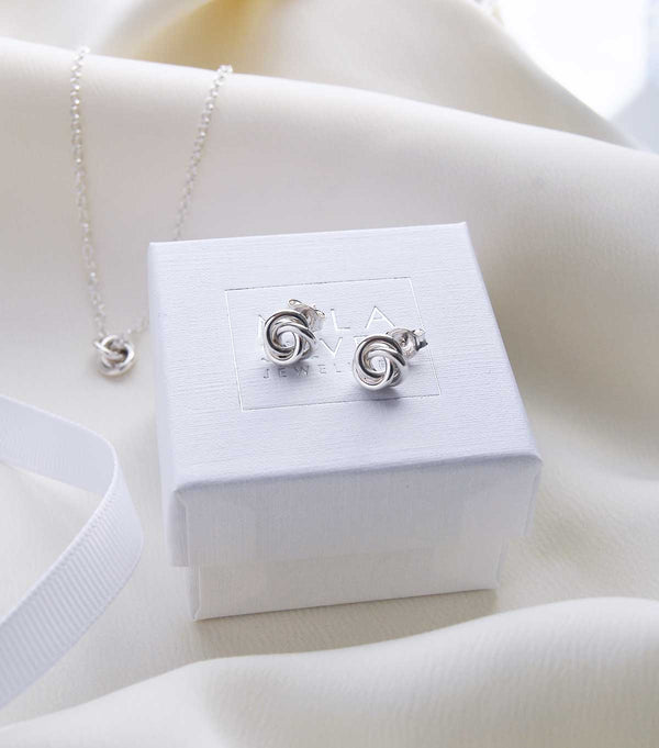 Små fasta silverörhängen med knutar som ligger på en smyckesask från Mila Silver. 