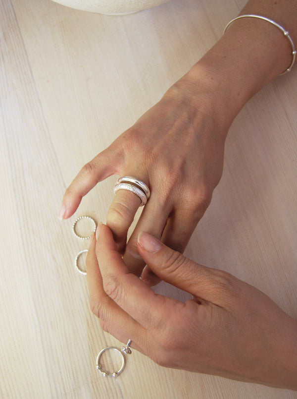 Två ringar i kombination, en blank och en hamrad silverring. 