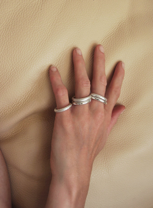 En hand med flera massiva silverringar på olika fingrar. 