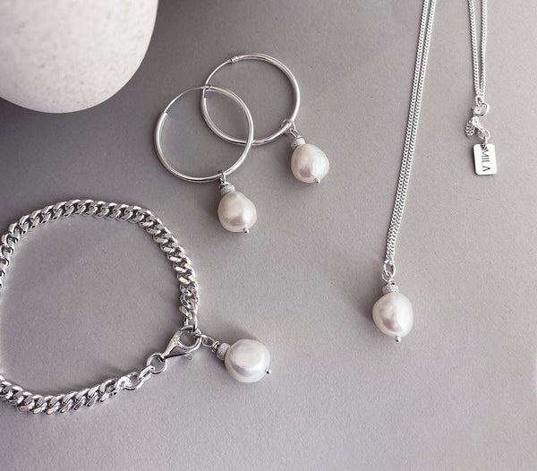Silversmycken med vita pärlor på armband, öronringar och halskedja. 